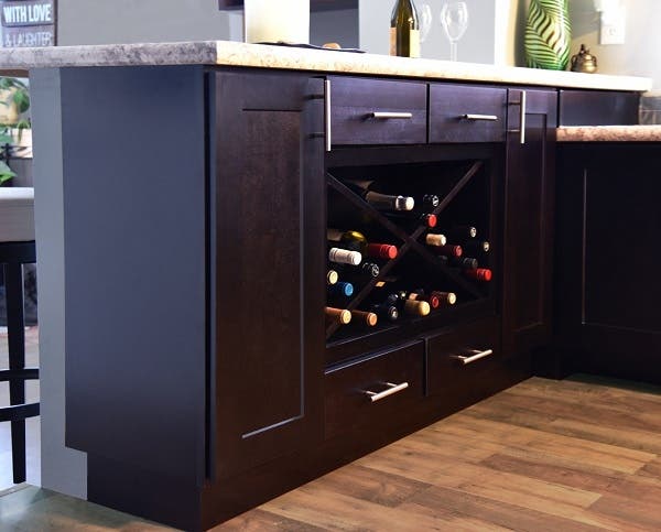 kitchen peninsula built of black-stained birch cabinets has large wine rack and single drawers