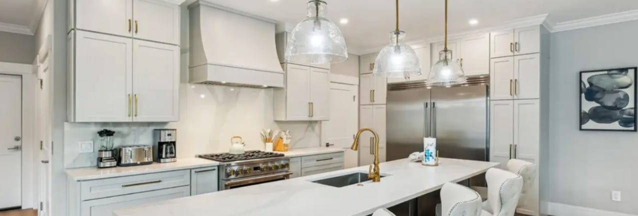Newport Mist and Timber kitchen cabinets Light gray shaker kitchen cabinets with a dark wood island and gold cabinet hardware
