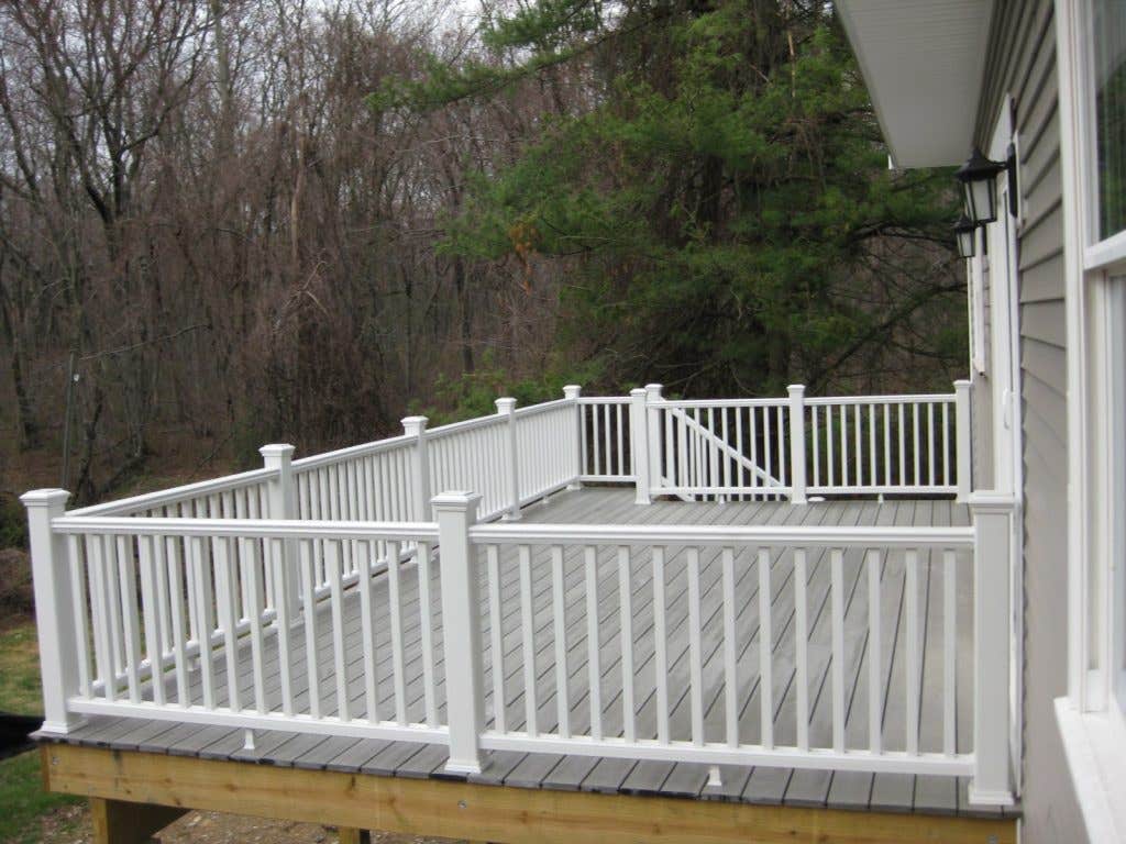 deck on new home has white railing and overlooks wooded Connecticut countryside.